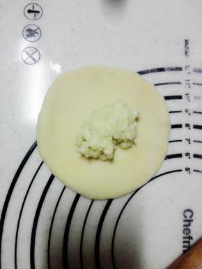 取一个面团，擀开，放入20克榴莲，用虎口的位置包裹起来，收口朝下