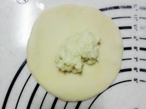 取一个面团，擀开，放入20克榴莲，用虎口的位置包裹起来，收口朝下