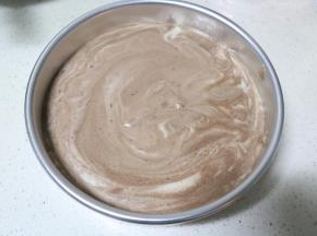 将蛋糕糊倒入模具中，提起模具在桌子上振三下，振出大气泡