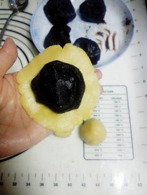 取一个面团，在手心压扁，放一颗枣泥馅