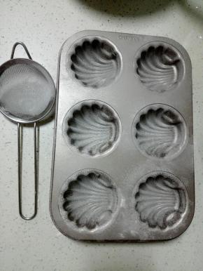 贝壳模具内抹上一层黄油，再筛上一层高粉（此步是为了纹路更好看，也更好脱模）