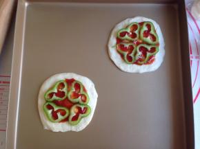 在圆形面片上涂上番茄酱，放上青椒圈