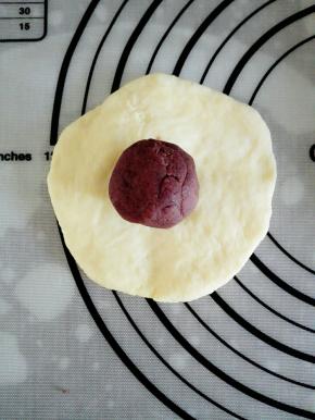 取一个面团，压扁后，放上一颗豆沙馅