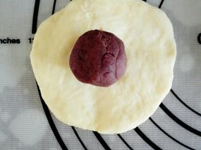 取一个面团，压扁后，放上一颗豆沙馅