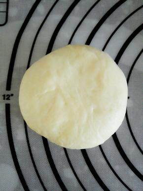 将豆沙馅包裹住，收紧口子，稍微压扁，收口朝下