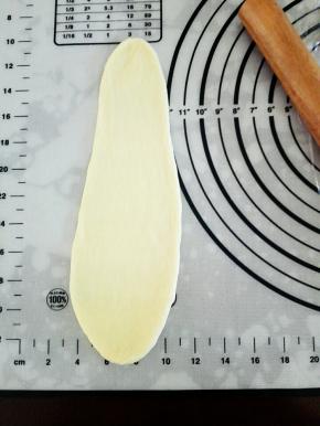 用擀面杖将萝卜头状面团擀成上窄下宽的面皮