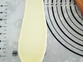 用擀面杖将萝卜头状面团擀成上窄下宽的面皮