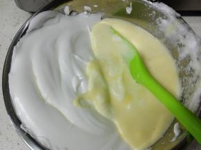 然后将蛋白全部倒入蛋黄糊盆中，翻拌均匀