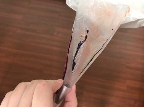 制作马卡龙。先将中号圆形花嘴放入裱花袋，用牙签粘点色素，沿着裱花袋拉一条线。你想做什么颜色就拉几条。