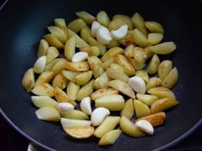 不粘锅热油，放入土豆角和蒜瓣煎金黄