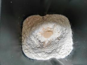 先打入一个鸡蛋，然后倒入牛奶，液体总量到达80g（我是预留20%牛奶，根据面粉吸水性慢慢加入），然后两个不同的角落放入糖和盐，倒入高筋面粉、全麦粉，上面挖一个小坑放入1.5g酵母，开启揉面模式，15分钟。