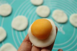 取一个冰皮，按扁，放入一个奶黄馅。