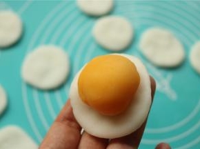 取一个冰皮，按扁，放入一个奶黄馅。