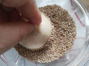 拿着刷了蛋清的面团去粘芝麻
