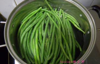 豇豆摘洗干净切大段放煮锅里焯烫熟，捞出来过凉水；