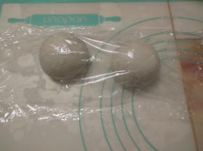 按揉面团排气后，分割成两份，揉圆后加盖保鲜膜醒15分钟。