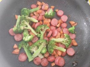 平底锅里倒入少许橄榄油，先加入切碎胡萝卜炒软，再放入切成块的脆皮肠、适量盐和黑胡椒碎炒匀离火。加入焯好水的西兰花拌一下。