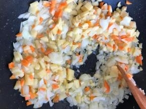 炒软后加入土豆胡萝卜丁，继续炒两分钟