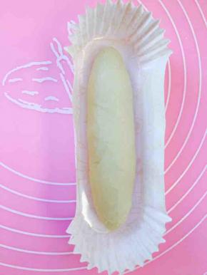 将侧卷的面团放置于船型纸膜中间位置，用手轻轻将它按扁一点，不要太用力，送它去二次发酵，时间大概60至70分钟