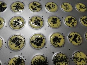 在学厨马卡龙模具上挤出圆形，撒上黑芝麻