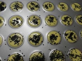 在学厨马卡龙模具上挤出圆形，撒上黑芝麻