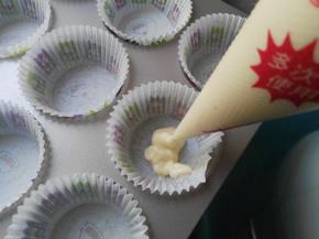 混合好的面糊装入裱花袋，裱花袋剪一小口，将面糊挤入纸托内