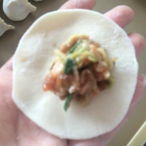 饺子皮中间包入拌好的饺子馅，再将边缘对折捏紧。