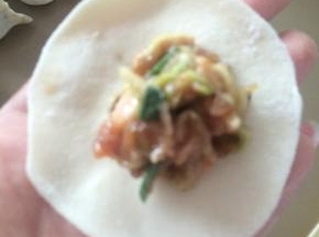 饺子皮中间包入拌好的饺子馅，再将边缘对折捏紧。