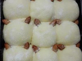 放入烤箱进行二次发酵，烤箱底层放一盘热水，发酵约30分钟至两倍大小，取出，在面团表面筛一层薄薄的高粉