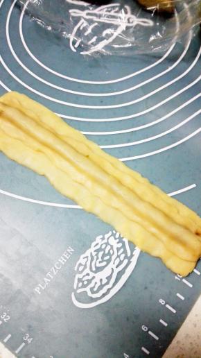 取12克原味面团搓成15cm的长条，压扁，覆盖在熊猫的鼻子上，完全覆盖