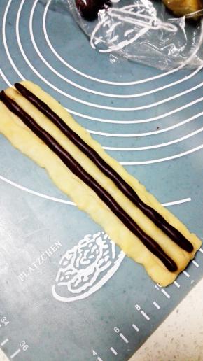 取两个各7克的可可面团，分别搓成15cm的长圆条放在鼻子的两侧，这是熊猫的眼睛