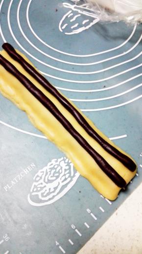 再将剩余的可可面团分成两份，搓成条放置在11上，熊猫耳朵部分完成