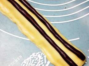 再将剩余的可可面团分成两份，搓成条放置在11上，熊猫耳朵部分完成