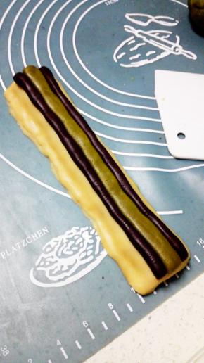 取14克抹茶面团，搓圆压成长条状，放在两个可可条中间