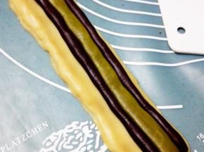 取14克抹茶面团，搓圆压成长条状，放在两个可可条中间