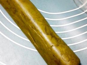 将剩余所有的抹茶面团，搓圆按扁成条状，完全包裹住之前做的熊猫胚，四面都要包住，包上保鲜膜，入冰箱冷冻30分钟