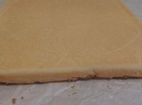 烤好的蛋糕震一下，连这油纸一起拿出来，趁热把油纸撒开，可以把油纸翻一个面再盖在上面，（不浪费）