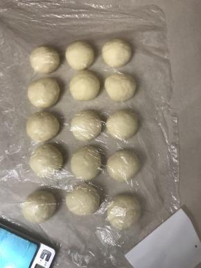 把松驰好的面团轻拍排气，分成15 份，滚圆盖上保鲜膜松弛10 分钟。