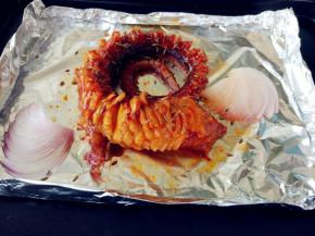 洋葱切花刀，和切好的章鱼足一起摆在烤盘上。可在烤盘上垫一张锡纸，周围稍捏起做成简易的锡纸盘