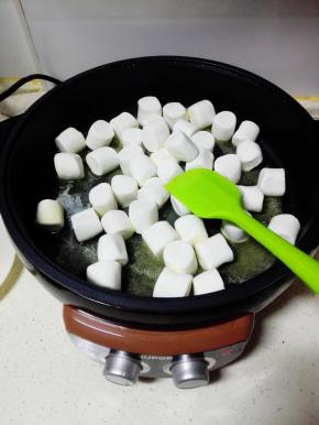 改小火，倒入棉花糖，慢慢搅拌至棉花糖和黄油融化在一起。