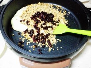 倒入碎花生米，蔓越莓干，关火，用手充分揉匀。 注意烫手