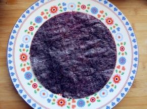 将用来做寿司的烤紫菜放在砧板上，将一个大小合适的盘子倒扣在上面，用小刻刀沿四周划一圈，去掉多余的部分后，铺在大盘内