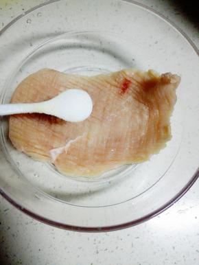 将放松好的两块鸡胸肉放入料理碗中，加入1茶匙盐，抹匀