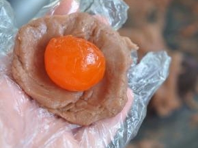 把香芋馅取25克，压扁后放入咸蛋黄，包起来。真空包装的咸蛋黄，使用前需要在油里浸泡三天。