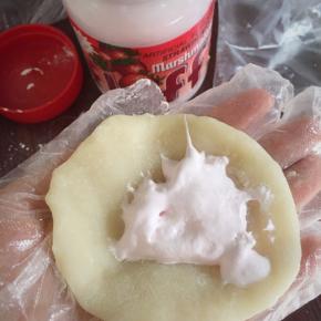 裹上一汤勺Fluff 草莓味棉花糖，将雪媚娘皮从四周向中间折叠，将棉花糖包裹住