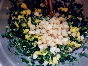 将扇贝丁用少许盐/料酒/生抽抓匀，入不粘锅中，小火用少许油煎一下，然后连油和扇贝丁一起倒入韭菜和鸡蛋中拌匀