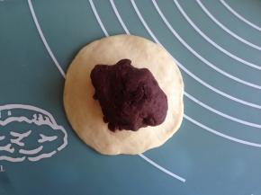 40克面团用手压一下成圆形，光滑面朝下，中间厚，边缘簿，将25克的豆沙馅放入中间，收口。