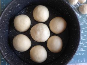 收口朝下，50克面团包入50克的豆沙馅。将做好的面包坯放入到8寸圆形的不粘模里，大的面包坯放中间，每个都留有空隙，如图摆放。