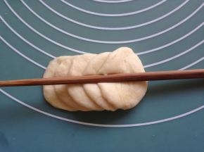 另10克的面团擀圆，五片叠放在一起，用筷子在中间压一下，从最后一片向内卷起来。然后在中间切一刀，做成两朵玫瑰花。