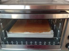 将拌好的蛋糕糊倒入到铺了油纸的法焙客正方形不粘烤盘里，可以用刮板将表面刮平。放入到已经提前预热好180度的烤箱下层，烘烤18分钟。烤好的蛋糕取出，放凉3分钟，再倒扣在另一张干净的油纸上，撕掉底部的油纸，放凉备用。